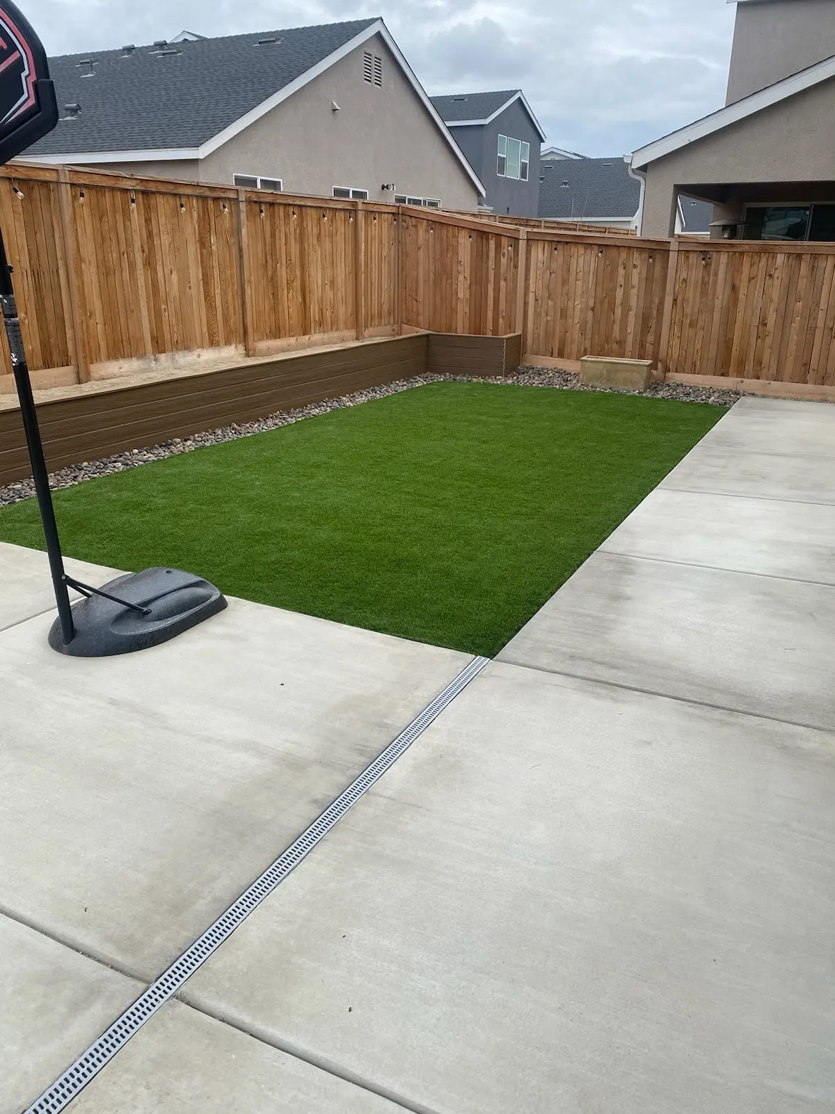 Fenced backyard with artificial turf, river rock border and a cedar privacy fence