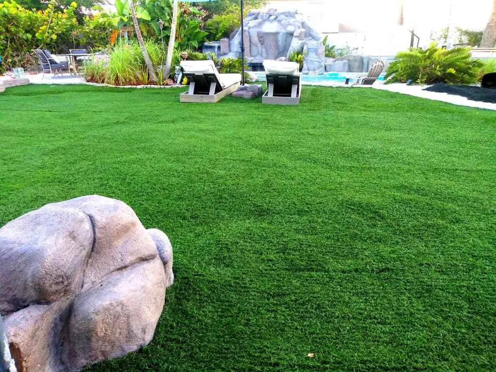 Poolside artificial lawn with lounge chairs and tropical plants