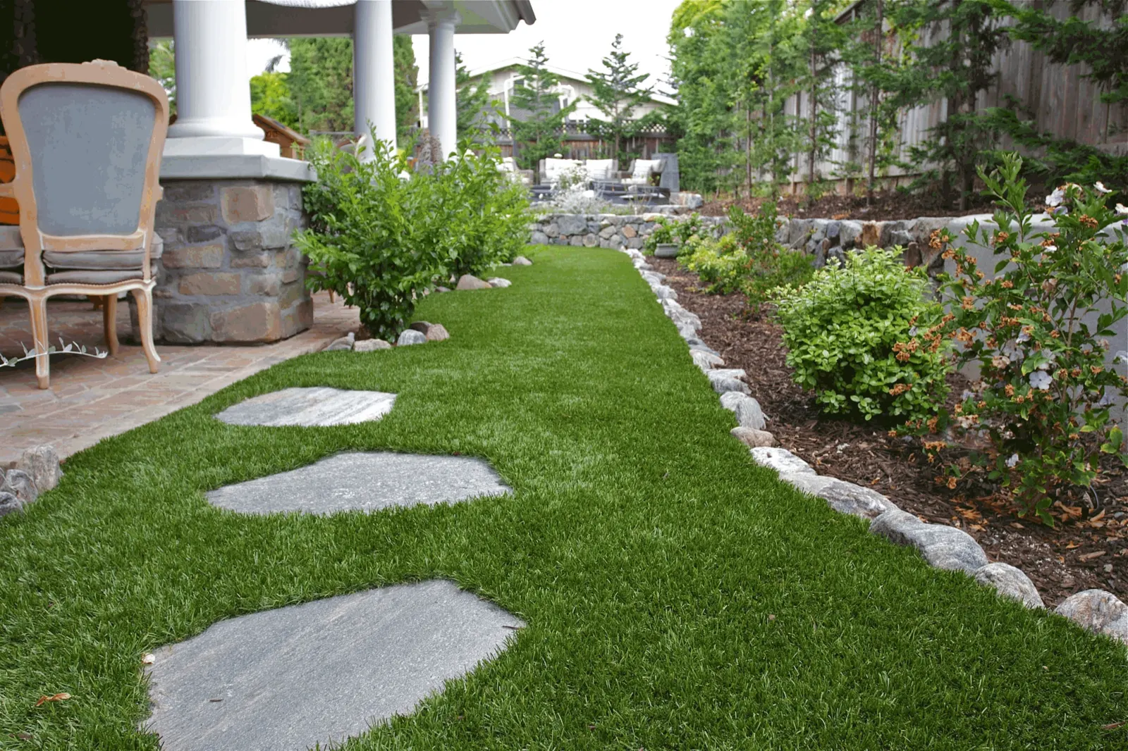 Side yard turf path with flagstone stepping stones and a rock border