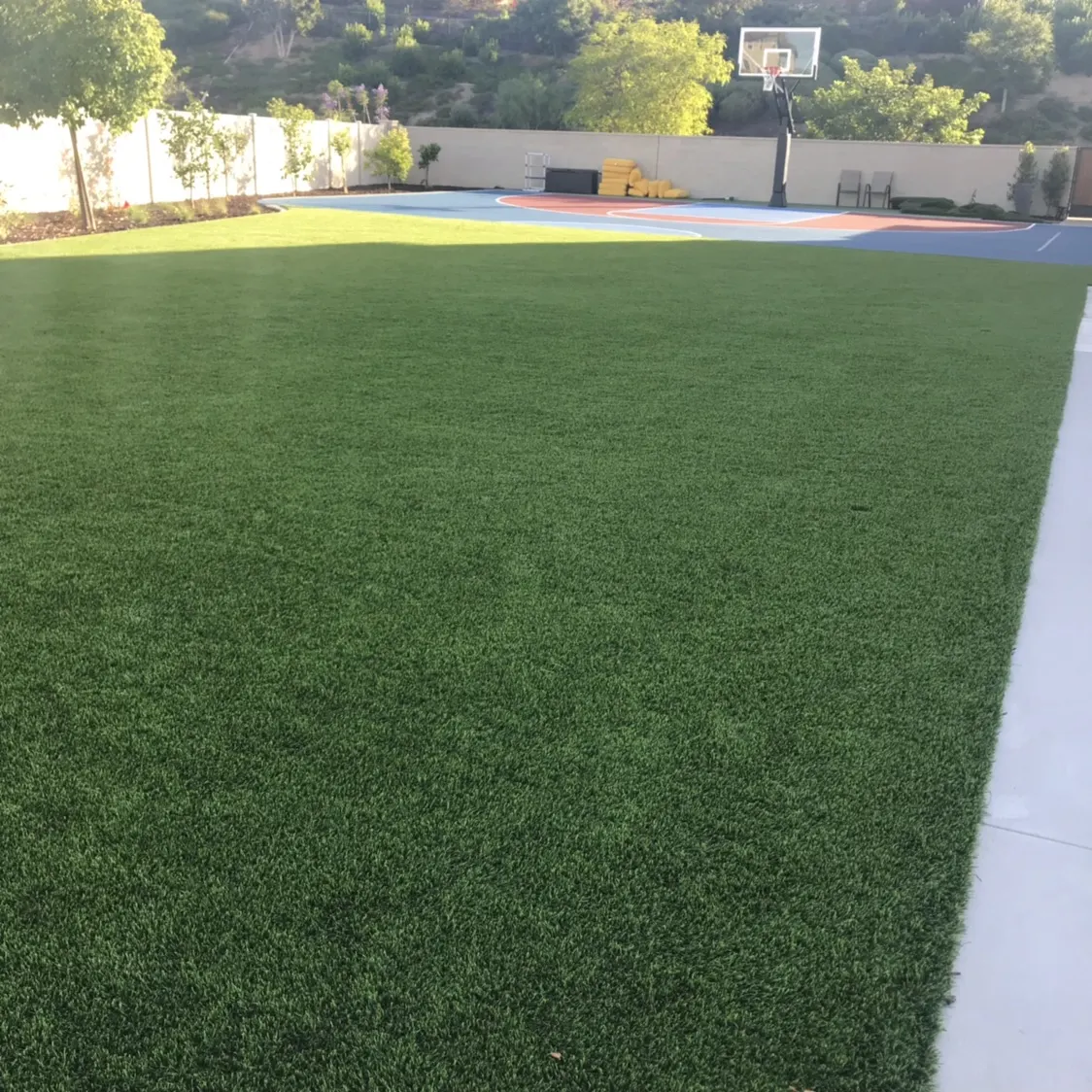 Open artificial turf play lawn next to a backyard basketball court